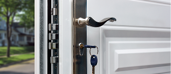 A residential door handle with a key hanging from the lock.