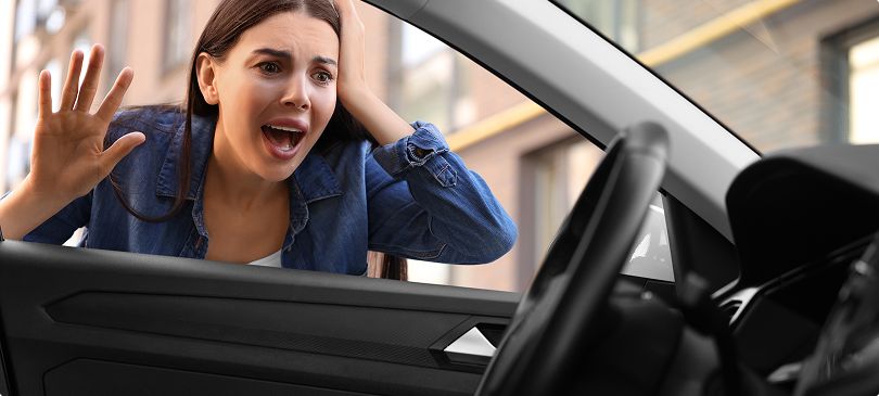 A concerned woman looking at her keys locked inside the car.